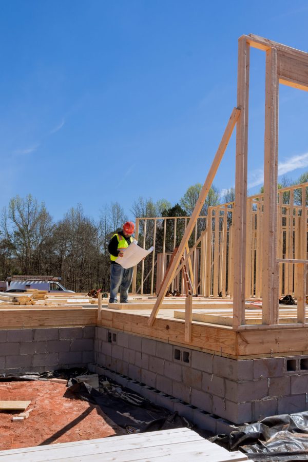 When construction project is underway safety inspector checks quality of work being performed on site using construction blueprint