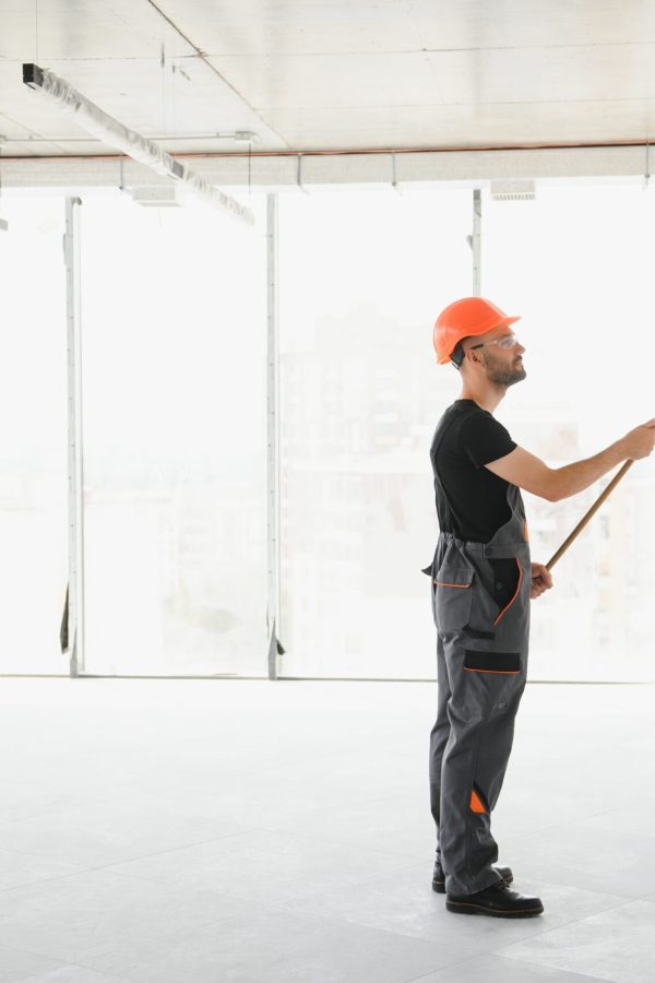 The man is painting the wall. DIY repair. The painter holds the roller near the wall.